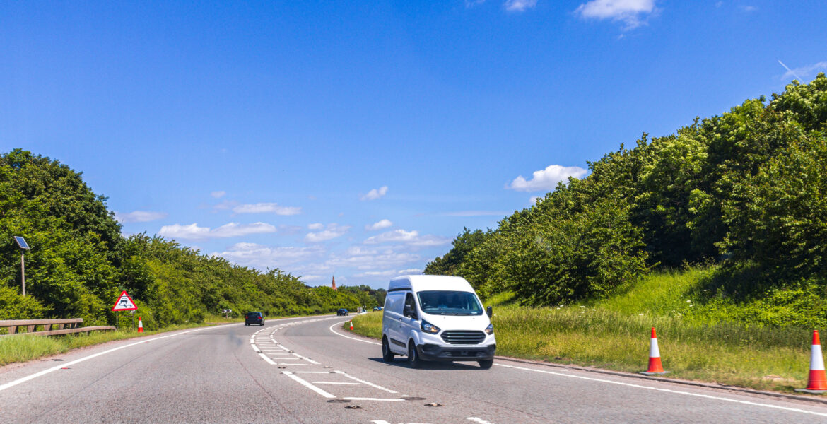 A small van vehicle traveling along one of the main road routes of the United Kingdom, on a summer's day. Taking goods to and from their suppliers and customers.